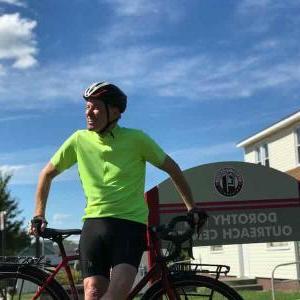 沙姆斯·麦克格伦弟兄在多萝西日间服务中心的招牌前和他的自行车合影